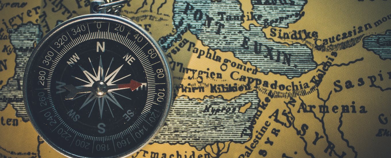 A close up of a compass pointing east, placed on a map