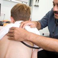 A specialist listens to a boy's back with a stethoscope
