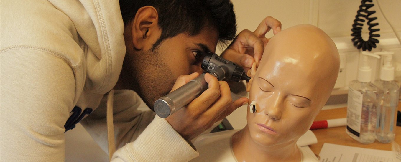 student examining a dummy's ear