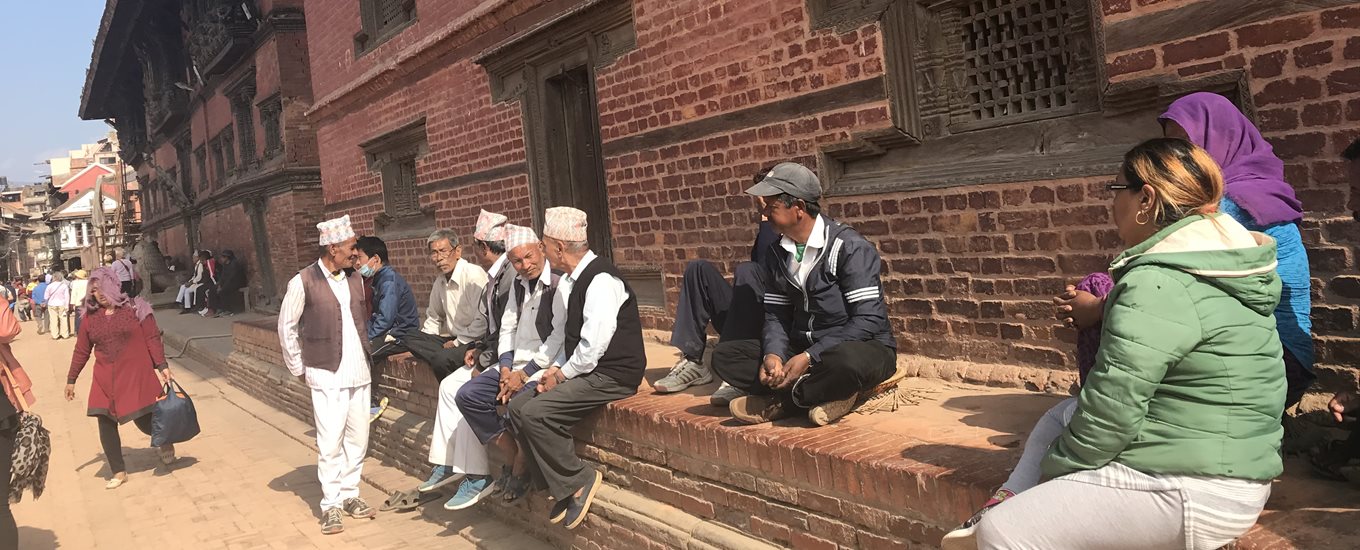 People sitting on steps outside a building in Nepal