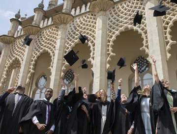 Graduating students in front of Brighton Dome, throwing mortar boards in the air