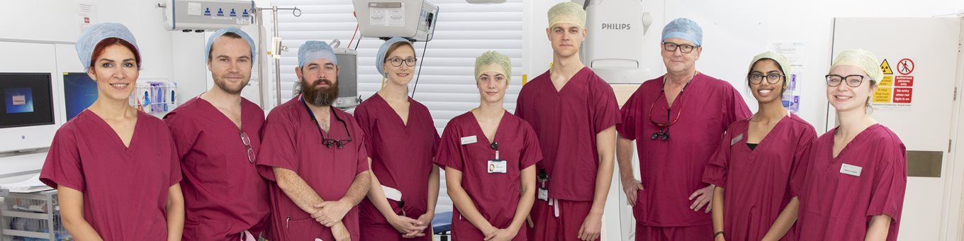 Student doctors and hospital staff in scrubs in operating theatre