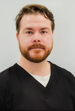 A head and shoulders shot of Luke Reid from the BSMS anatomy team wearing black scrubs