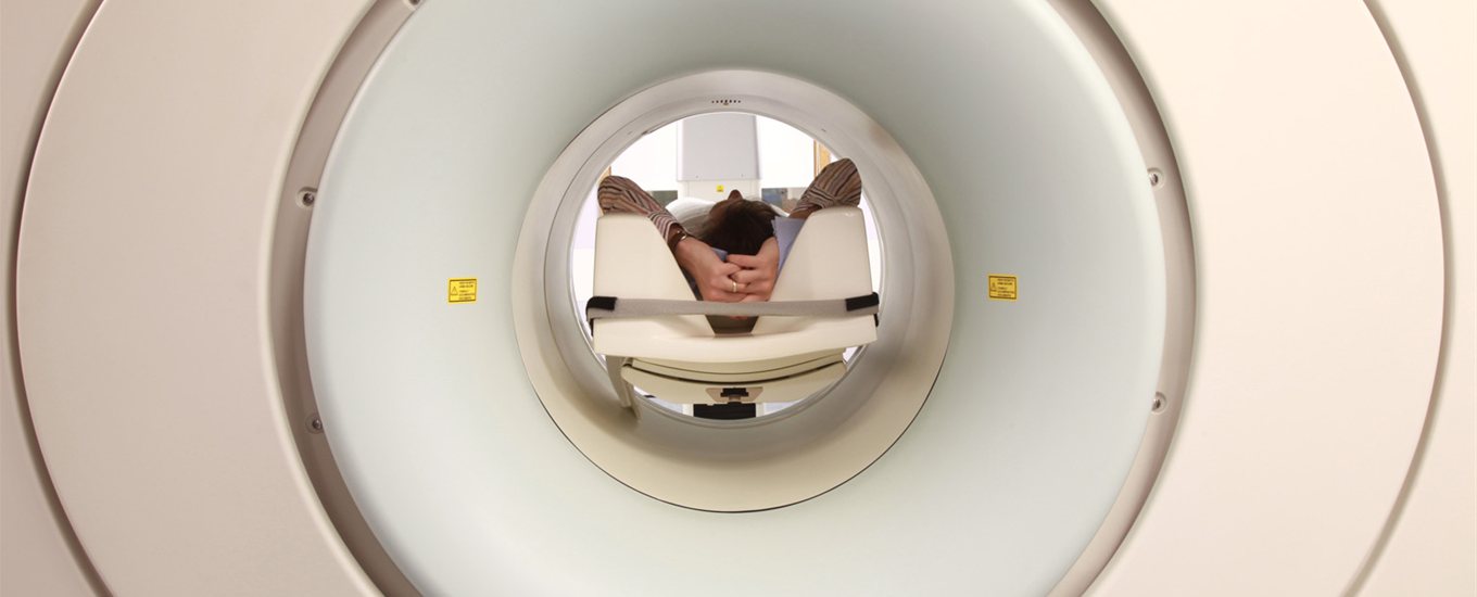 Patient inside an MRI scanner with their hands behind their head
