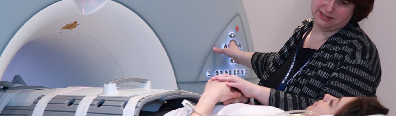 A Dr holding the hand of a patient about to go into an MRI scanner