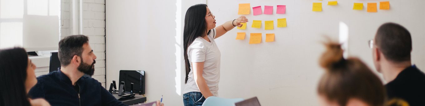 People in an office looking at post it notes on a wall