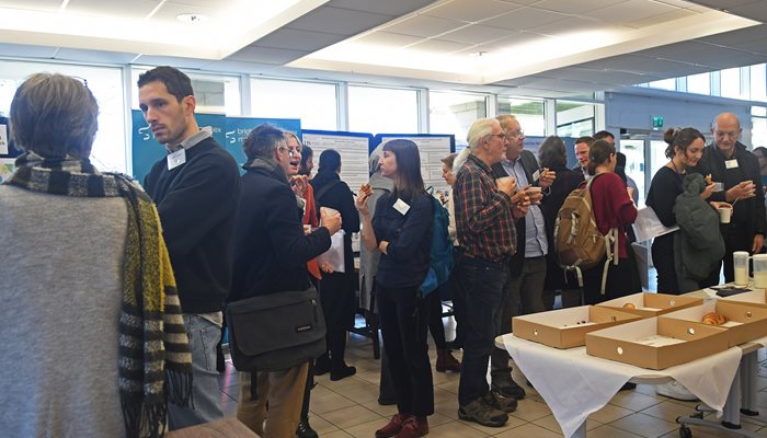 A group of people in a foyer talking next to poster boards at the CISC open day in 2022