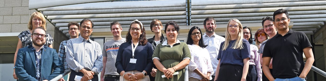 A group of people stood outside on steps looking at the camera and smiling