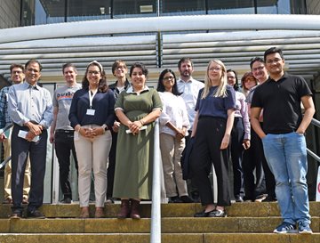 A group of people stood outside on steps looking at the camera and smiling