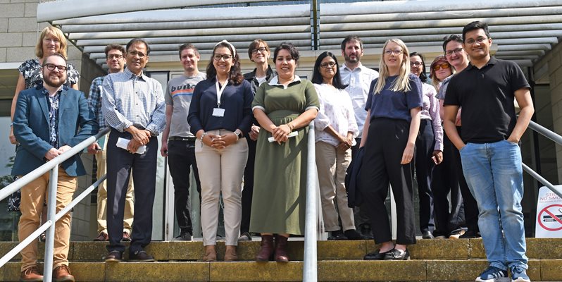 A group of people stood outside on steps looking at the camera and smiling