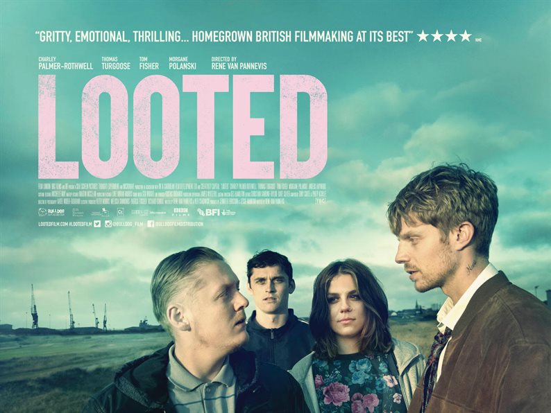 Mid shot of four people stood in a deserted landscape with the film title 'Looted' and cast details written on it