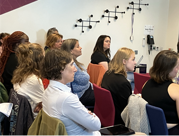 A group of people in a workshop listening to a talk