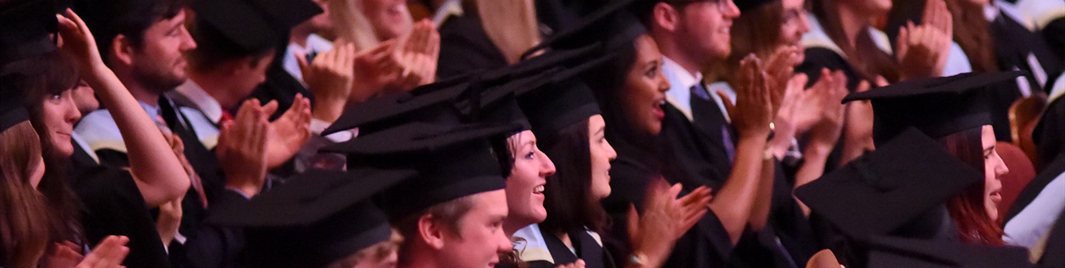 Clapping students in gowns at graduation