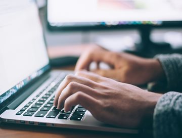 Hands typing on a laptop keyboard