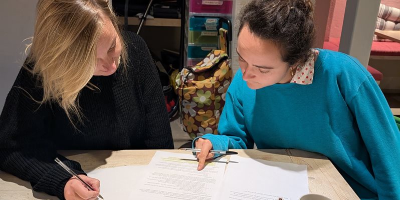 Two people in conversation at a table looking down at paperwork