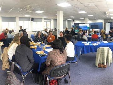 A large room of people at an event sitting around tables