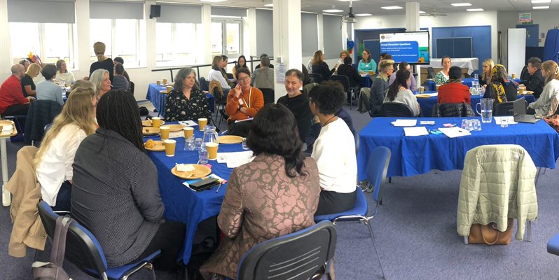 A large room of people at an event sitting around tables
