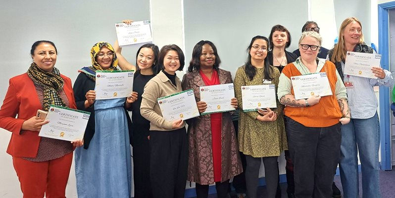 A group of people at an event holding up certificates and smiling
