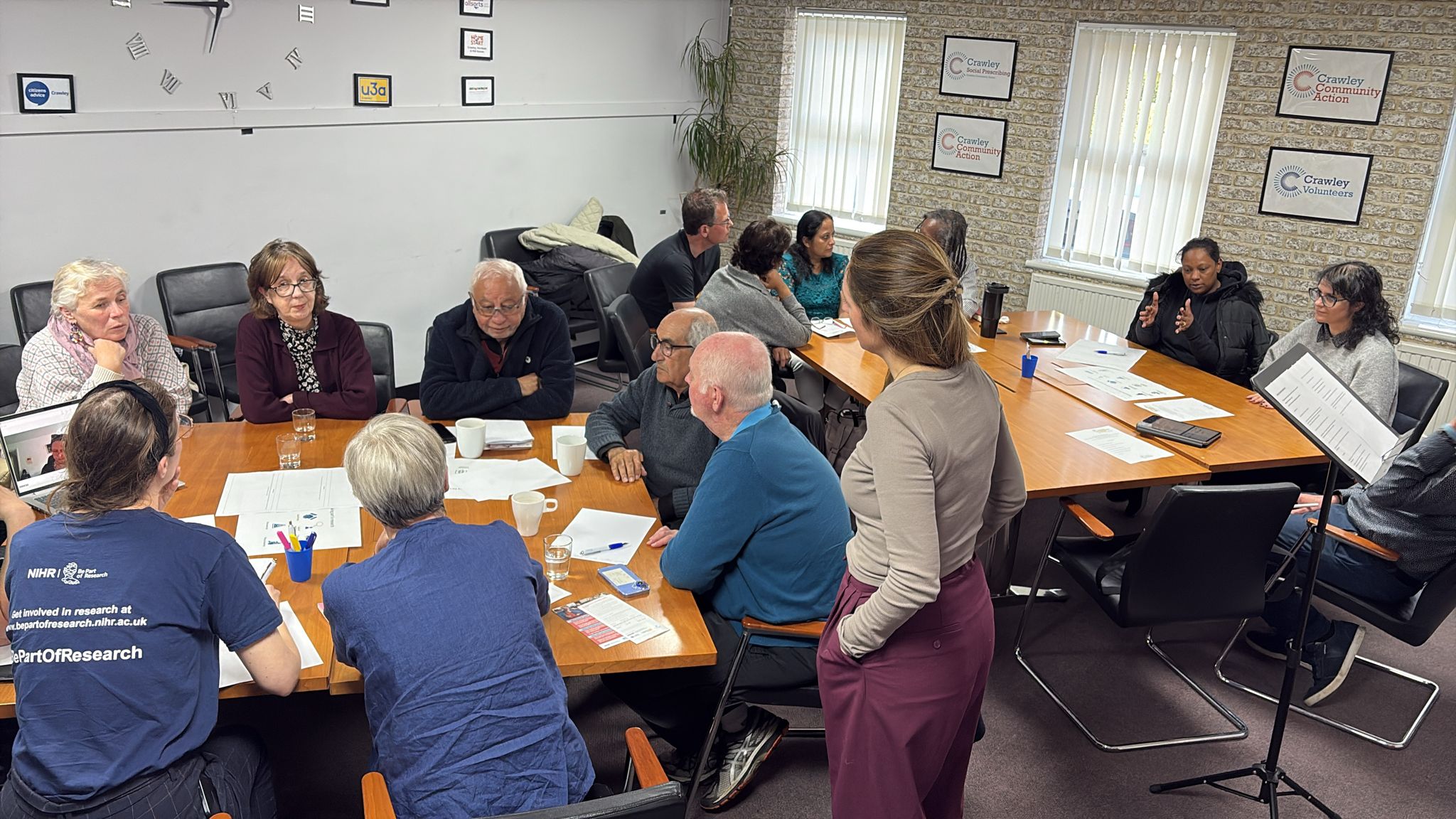 A group of people in Crawley discussing community health and research around a table