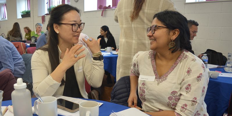 Two people talking and smiling at a table during an event