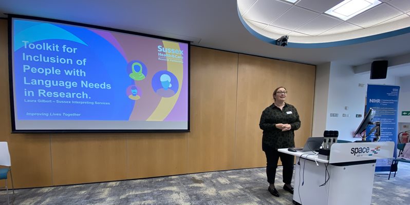 A person presenting in front of a lectern and screen during an event