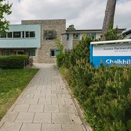 A building with a blue NHS sign and green grass outside of it next to a pathway