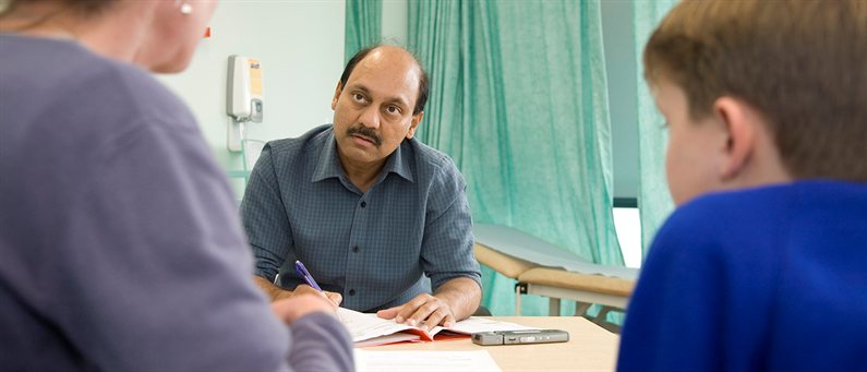 A child and his mother attending an asthma consultation. The Dr listens and takes notes.