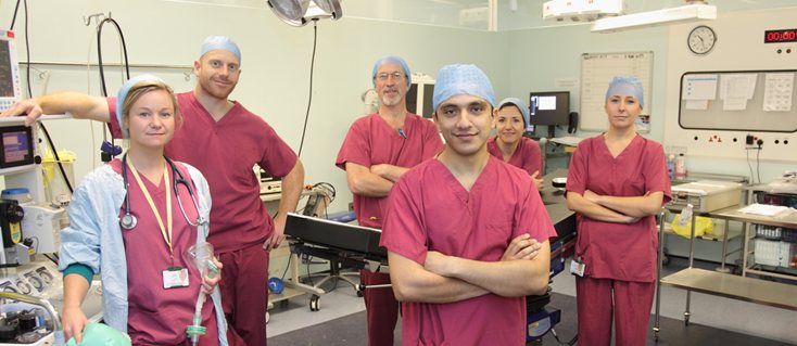 Students in scrubs with medics in an operating theatre
