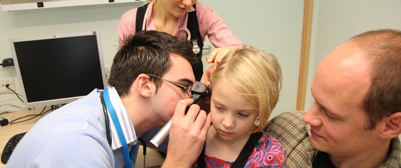 student examines childs ear