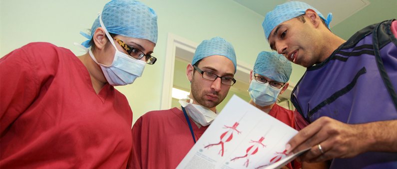 A surgeon talks to students in scrubs