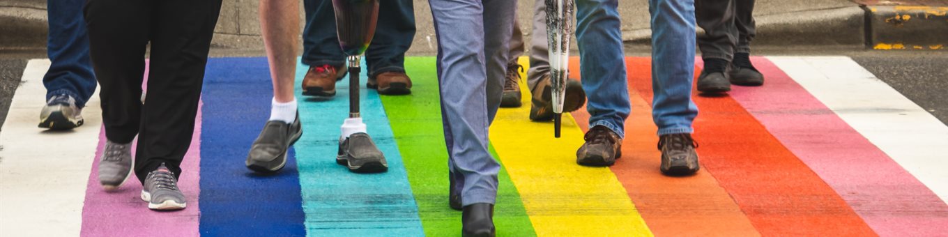 group of people crossing a rainbow zebra crossing