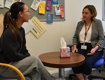 Student and student advice staff member sitting across a table having a conversation