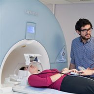 A student talks to a woman in the MRI scanner