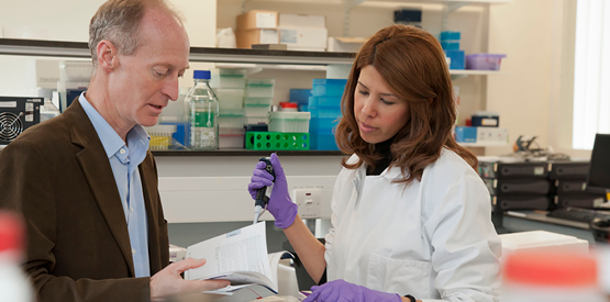 Tim Chevassut and student in a lab looking at a book