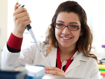 Female researcher holding a pipette and smiling