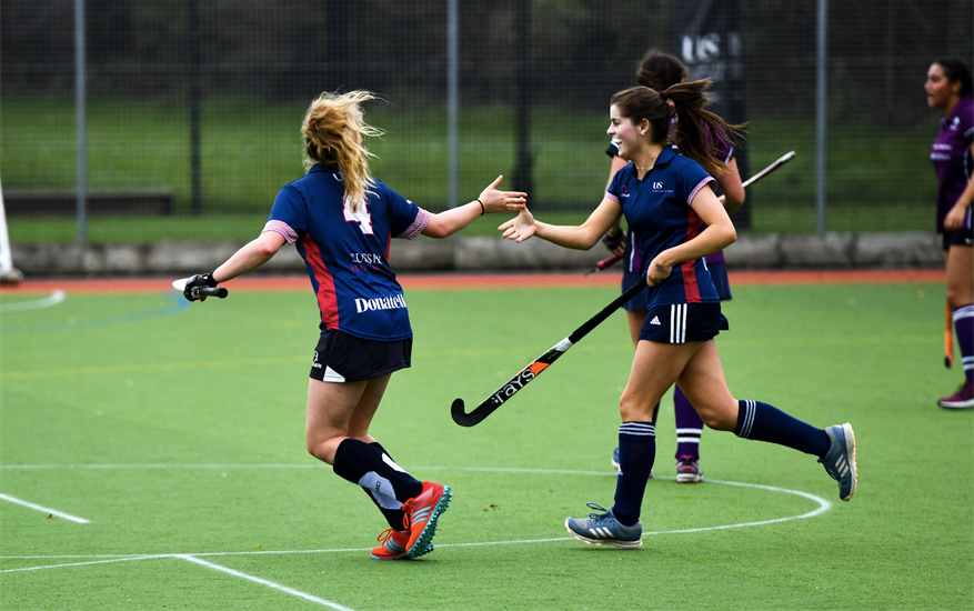 People running around on a pitch playing hockey