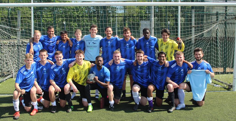 A group of BSMS students posing for a team photo in matching football shirts before playing football