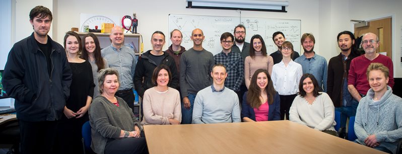 Consciousness science staff sitting and standing around a table