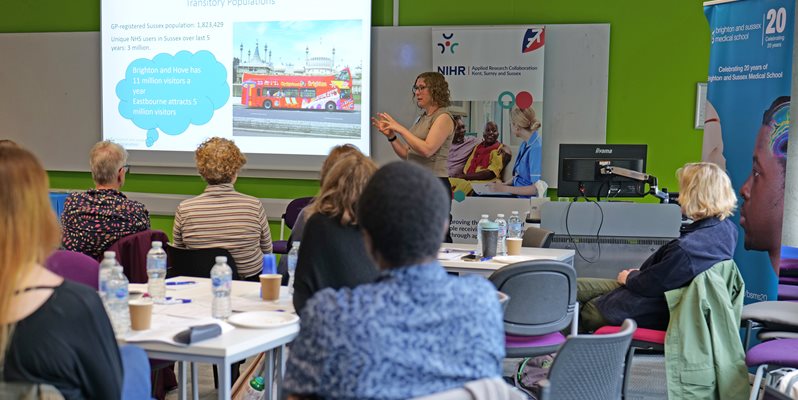 A group of people listening to a talk with a screen in the background