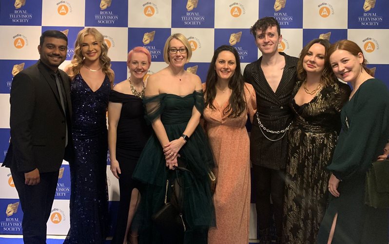 The BSMS Anatomy team pictured at RTS awards 2023 stood as a group in front of advertising/logo signage for a photo