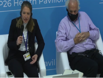 A woman and a man pictured at the COP26 event on a stage in Glasgow with microphones
