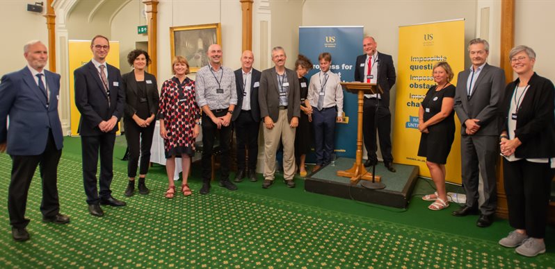 A group of Centre directors around a podium in parliament for the launch of the centre for global health research centre of excellence