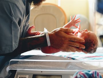 A new born baby being placed on a mat by a nurse or doctor in blue scrubs