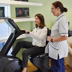 A woman on an exercise bike with and instructor for a programme promoting positive living for people with HIV