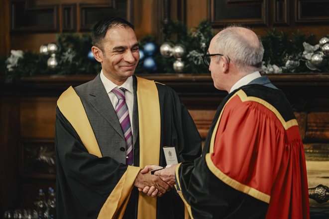 Mahmood Bhutta shaking hands with someone giving him an award