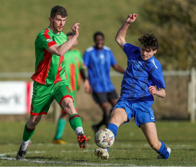 Two people tackling each other over a football on a field