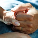 a close up of two people holding hands in a supportive manner