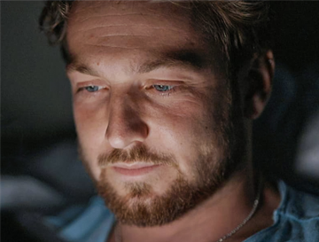 Sam Thompson, looking at his phone. This is a promotional photo to promote his new ADHD documentary