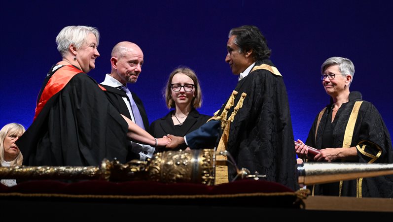 People on stage at a graduation ceremony shaking hands