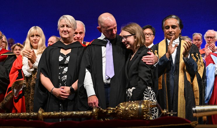 A group of people on stage at a graduation ceremony facing forwards